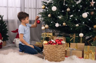 Evde Noel ağacı süsleyen şirin bir çocuk.