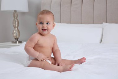 Evde beyaz yatakta kuru, yumuşak bebek bezi içinde şirin bir bebek.