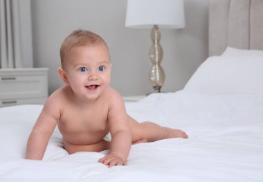 Evde beyaz yatakta kuru, yumuşak bebek bezi içinde şirin bir bebek.