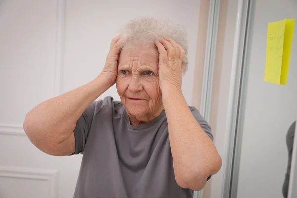 鏡の近くにいる忘れられない年配の女性は屋内で注意してください 年齢関連記憶障害 — ストック写真