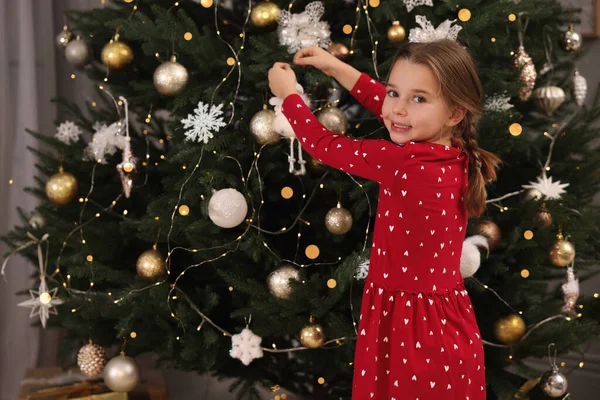 Evde Noel ağacı süsleyen şirin bir çocuk.