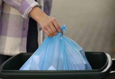 Dışarıdaki çöp kutusuna çöp torbası koyan kadın, yakın çekim.