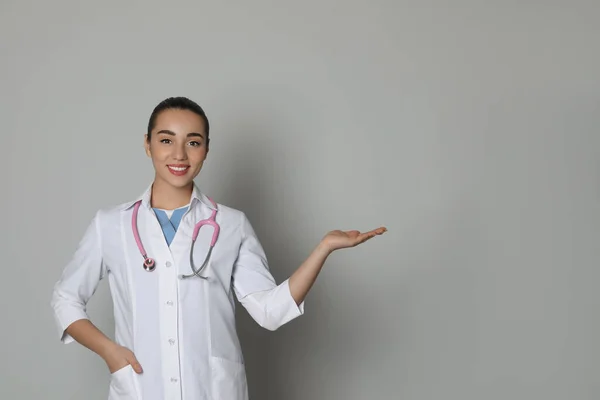 Beautiful Young Doctor Showing Something Light Grey Background — Stockfoto