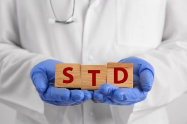 Doktor elinde tahta küplerle STD kısaltması taşıyor, yakın plan.
