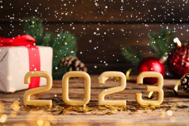 2023 numaraya kar yağıyor ve ahşap masaya şenlikli bir dekor, yazı için yer var. Mutlu yıllar.