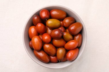 Taze Ziziphus jujuba meyveleri beyaz masa örtüsü üzerinde kasede.