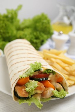 Beyaz ahşap masada servis edilen tavuk eti ve taze sebzeli leziz shawarma.