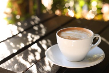 Açık kafedeki masada köpüklü bir fincan aromatik kahve. Metin için boşluk