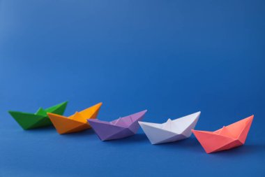 Mavi arka planda bir sürü renkli el yapımı kağıt tekne var. Origami sanatı