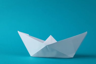 Açık mavi arka planda el yapımı beyaz kağıt tekne. Origami sanatı