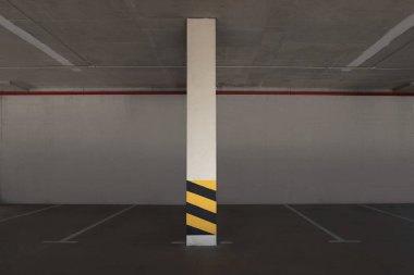 Sütununda uyarı çizgileri olan boş bir otopark.