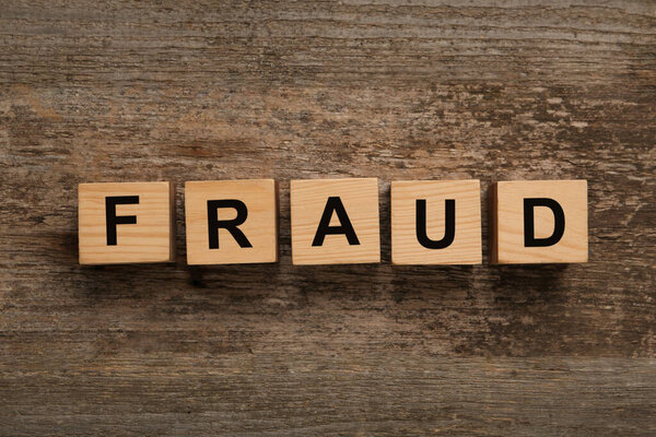 Wooden cubes with word Fraud on table, flat lay