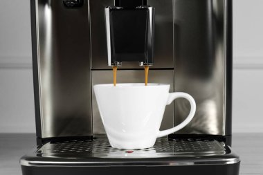 Espresso makinesi kahve bardağına damlatıyor, yakın plan.