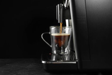 Gri masada, siyah arka planda modern espresso makinesiyle kahve yapmak. Metin için boşluk