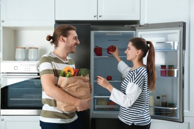 Mutfaktaki buzdolabının yanında yeni ürünleri olan çift.