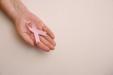 Arka planda pembe kurdele tutan son sınıf öğrencisi bir kadın. Üstü açık, mesaj için yeri var. Göğüs kanseri farkındalığı