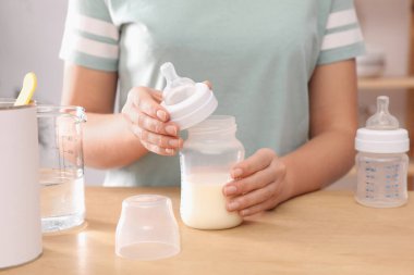 Masada bebek maması hazırlayan kadın, yakın plan. Bebek sütü