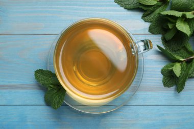 Açık mavi ahşap masa üzerinde bir fincan sıcak aromatik nane çayı.