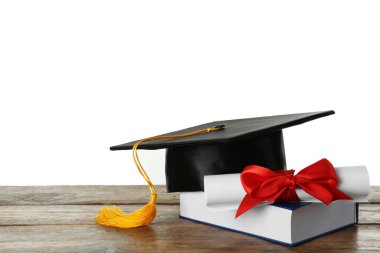 Mezuniyet şapkası, kitap ve diploması beyaz arka plana karşı ahşap masada.