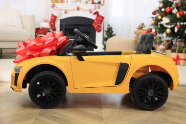 Noel için dekore edilmiş kırmızı fiyonklu çocuk elektrikli oyuncak arabası.