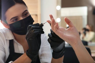 Müşteriyle kuaförde çalışan profesyonel manikürcü, yakın plan. Coronavirus karantinası sırasında güzellik hizmetleri