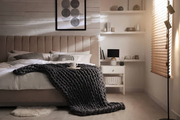 スタイリッシュな部屋のインテリアでベッドの上の柔らかいチュンキーニットブランケット — ストック写真