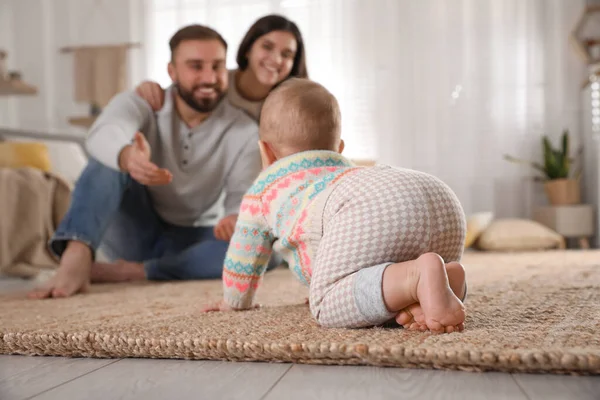 快乐的父母看着他们的孩子在家里的地板上爬行 — 图库照片