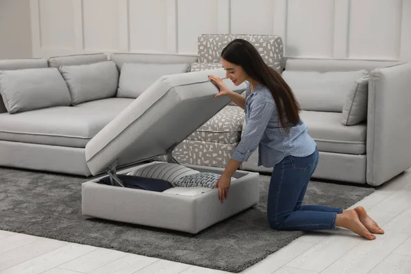 Woman opening modular sofa section with storage in living room