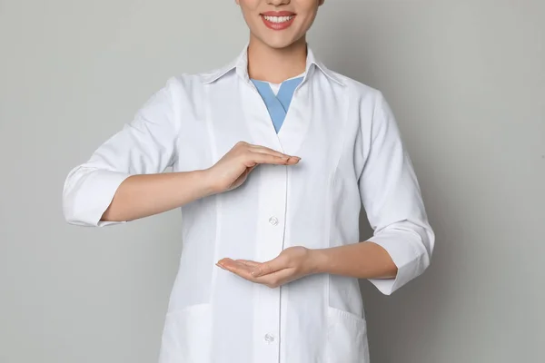 Joven Médico Sosteniendo Algo Sobre Fondo Gris Claro Primer Plano —  Fotos de Stock