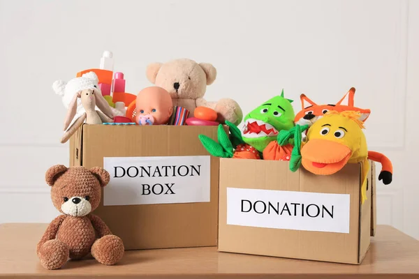 木桌上的捐赠盒和不同的儿童玩具 — 图库照片