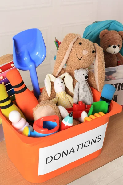 木桌上有不同儿童玩具的捐赠盒 — 图库照片
