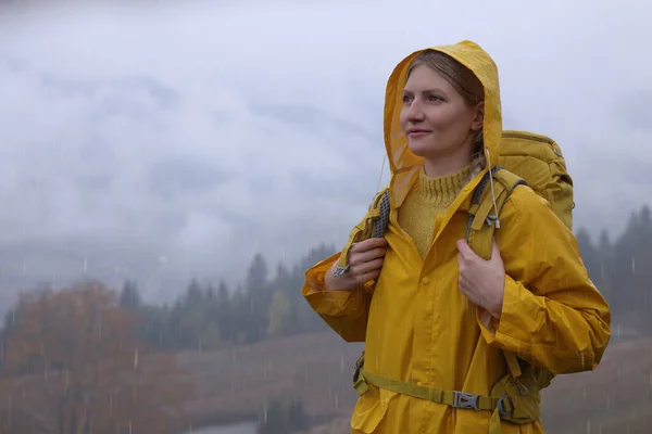 雨の下で山の景色を楽しむレインコートの若い女性 — ストック写真