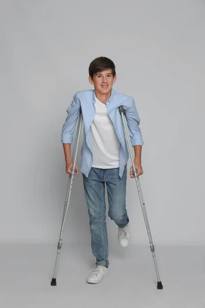 Teenage Boy Injured Leg Using Crutches Grey Background — Foto Stock