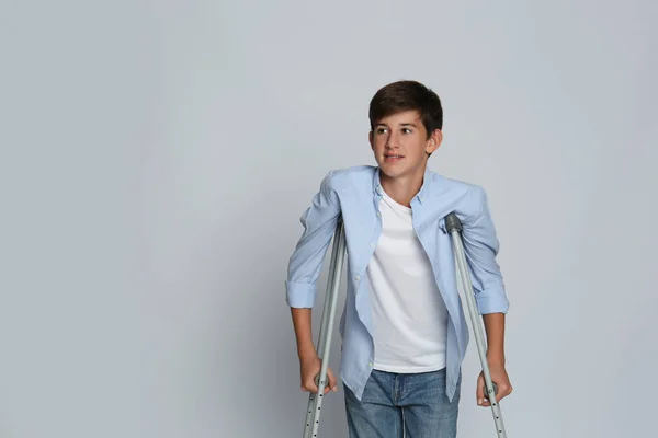 Teenage Boy Injured Leg Using Crutches Grey Background Space Text — Foto Stock