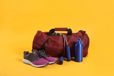 Sarı arka planda spor çantası ve spor malzemeleri.