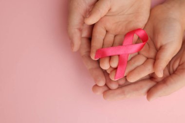 Kadın ve çocuğun elinde pembe kurdele var. Renkli arka planda. Üstten bakınca mesaj için yer var. Göğüs kanseri farkındalığı
