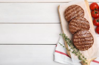 Lezzetli ızgara hamburger köfteleri, kiraz domatesleri ve beyaz ahşap masa üzerinde kekik, düz yatak. Metin için boşluk
