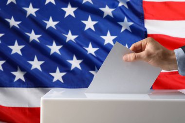 ABD 'de seçim. Adam oyunu sandığa ve arka planda Amerikan bayrağına koyuyor.