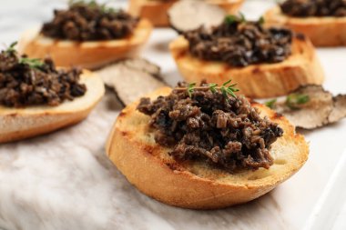 Yer mantarı soslu lezzetli bruschettalar ve beyaz masada kekik, yakın plan.