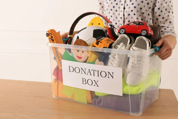 Mulher Segurando Caixa Doação Com Bens Criança Contra Fundo Leve — Fotografia de Stock