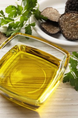 Cam kasede taze trüf yağı ve beyaz ahşap masada maydanoz, yakın plan.