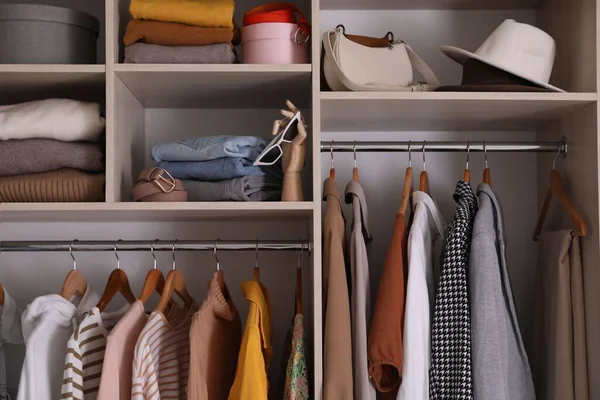 Wardrobe closet with different stylish clothes, accessories and home stuff