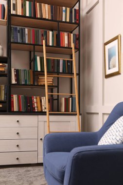 Ev kütüphanesinin içinde ahşap merdiven ve raflarda kitap koleksiyonu var.