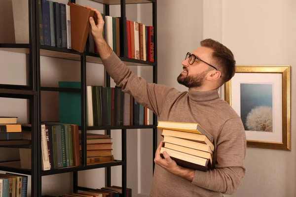 Młody Człowiek Wybierający Książki Półce Bibliotece Domowej — Zdjęcie stockowe