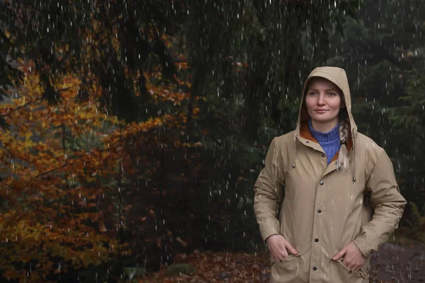 雨の下で森の中でレインコートを着た若い女性 — ストック写真