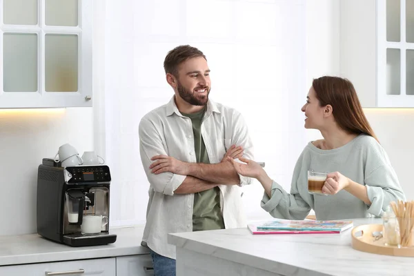Genç Adam Mutfakta Modern Kahve Makinesini Kullanırken Kız Arkadaşıyla Konuşuyor — Stok fotoğraf