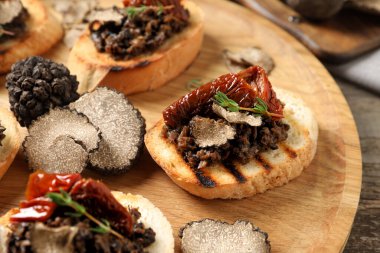 Mantar soslu lezzetli bruschettalar ve ahşap masada kurutulmuş domatesler, yakın plan.