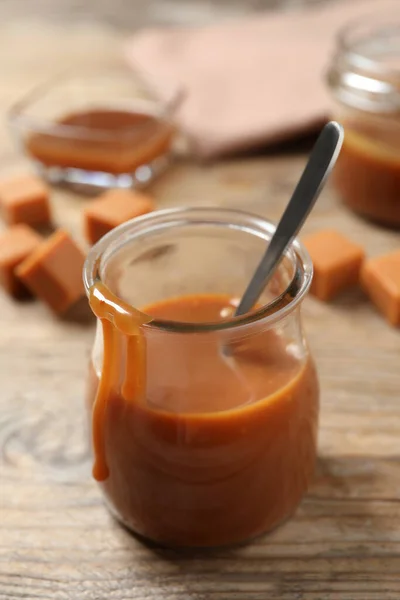 Tasty Salted Caramel Spoon Glass Jar Wooden Table — Stockfoto