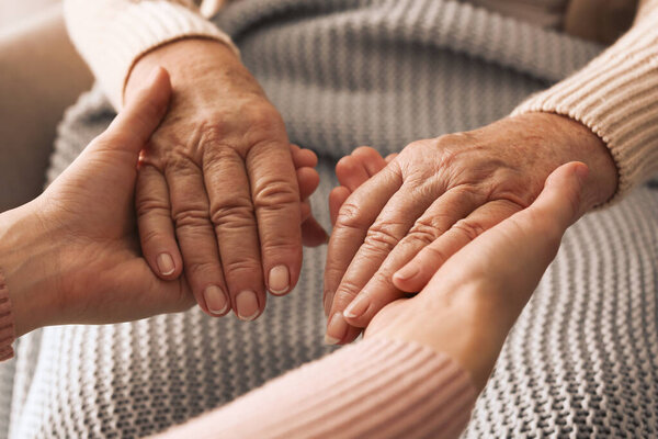 Young and elderly women holding hands together, closeup