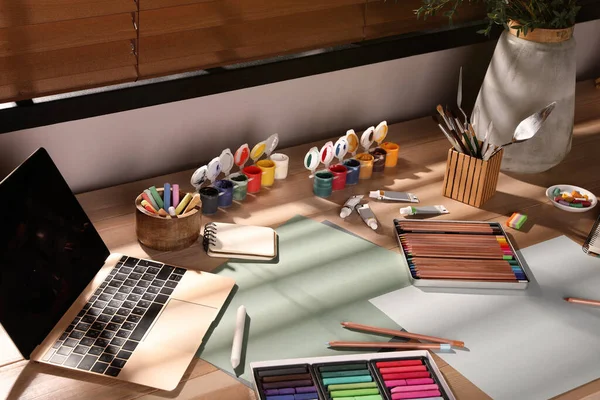Artist\'s workplace with soft pastels, laptop and drawing pencils on table